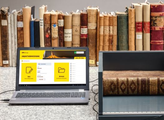 Buchvermessungsgerät mit Laptop vor einer Buchreihe